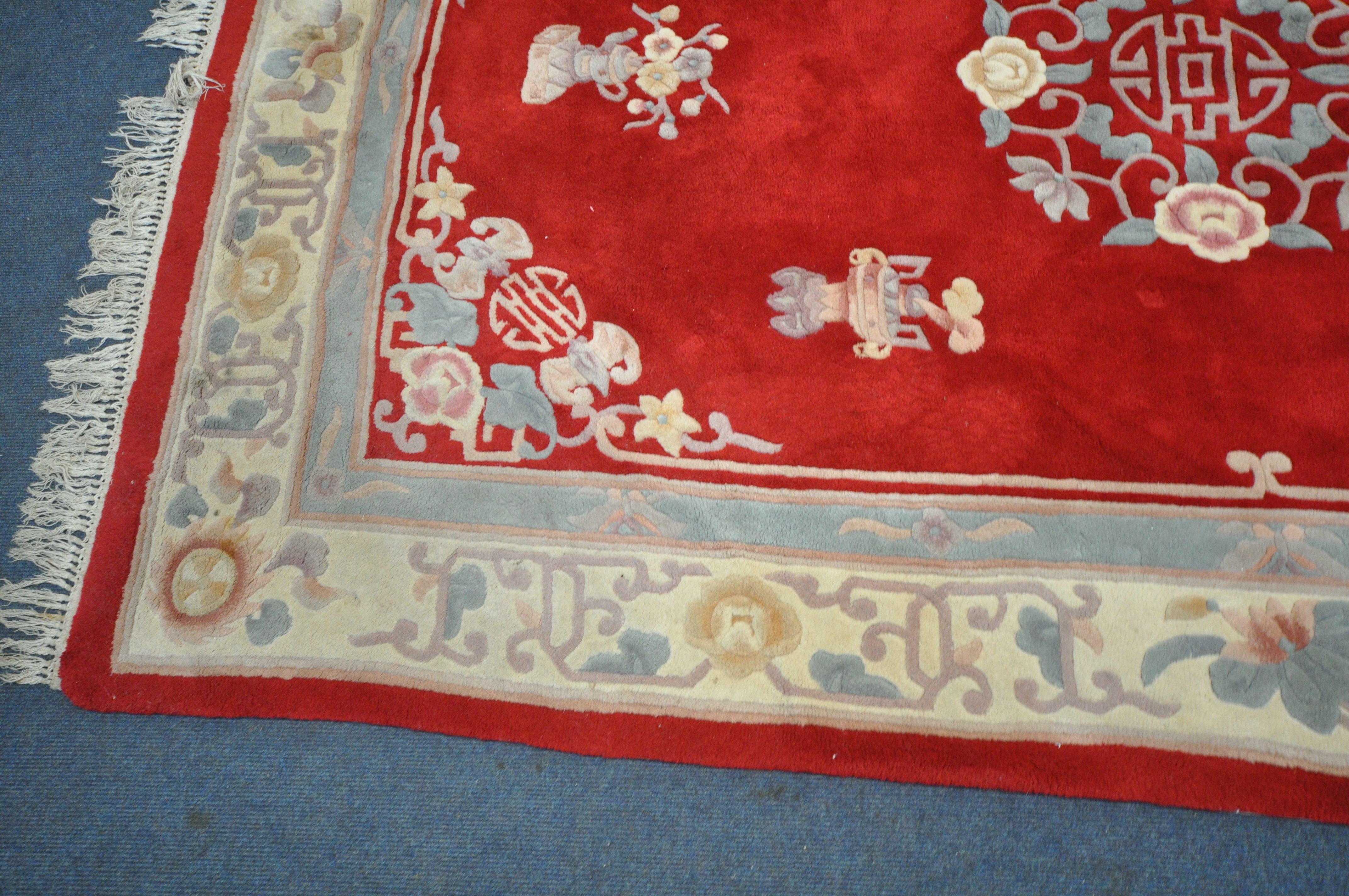 A RED GROUND WOOLEN RUG, with a multi strap border, and a central floral design 276cm x 190cm ( - Image 2 of 4