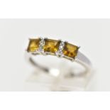 A WHITE GOLD GEM SET RING, set with three square cut yellowish/green stones, interspaced with single