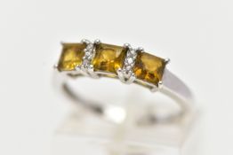 A WHITE GOLD GEM SET RING, set with three square cut yellowish/green stones, interspaced with single