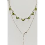 A WHITE METAL PERIDOT PENDANT NECKLACE, fitted with seven oval cut peridots each collect set into