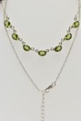 A WHITE METAL PERIDOT PENDANT NECKLACE, fitted with seven oval cut peridots each collect set into