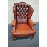 A GEORGIAN STYLE OXBLOOD LEATHER BUTTONED WING BACK ARMCHAIR, with swept armrests, on front cabriole