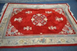 A RED GROUND WOOLEN RUG, with a multi strap border, and a central floral design 276cm x 190cm (