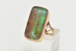 A 9CT GOLD BOULDER OPAL RING, of a rectangular form bolder opal displaying flashes of green, blue,