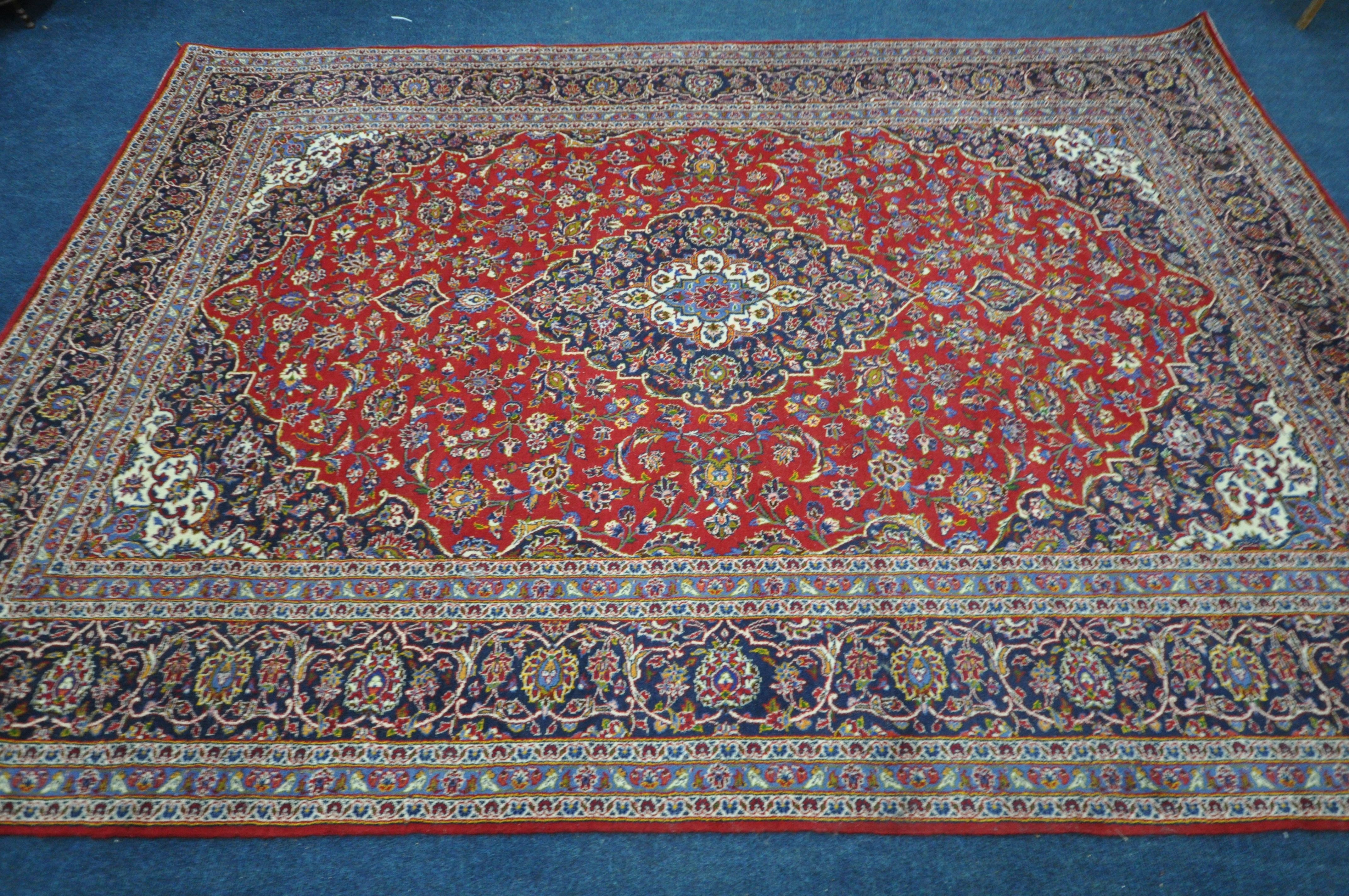 A 20TH CENTURY KASHAN RUG, with a central medallion, within a blue and red field, and a multi