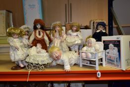 A COLLECTION OF TEN PORCELAIN COLLECTABLE DOLLS, to include a musical baby in a wooden highchair (