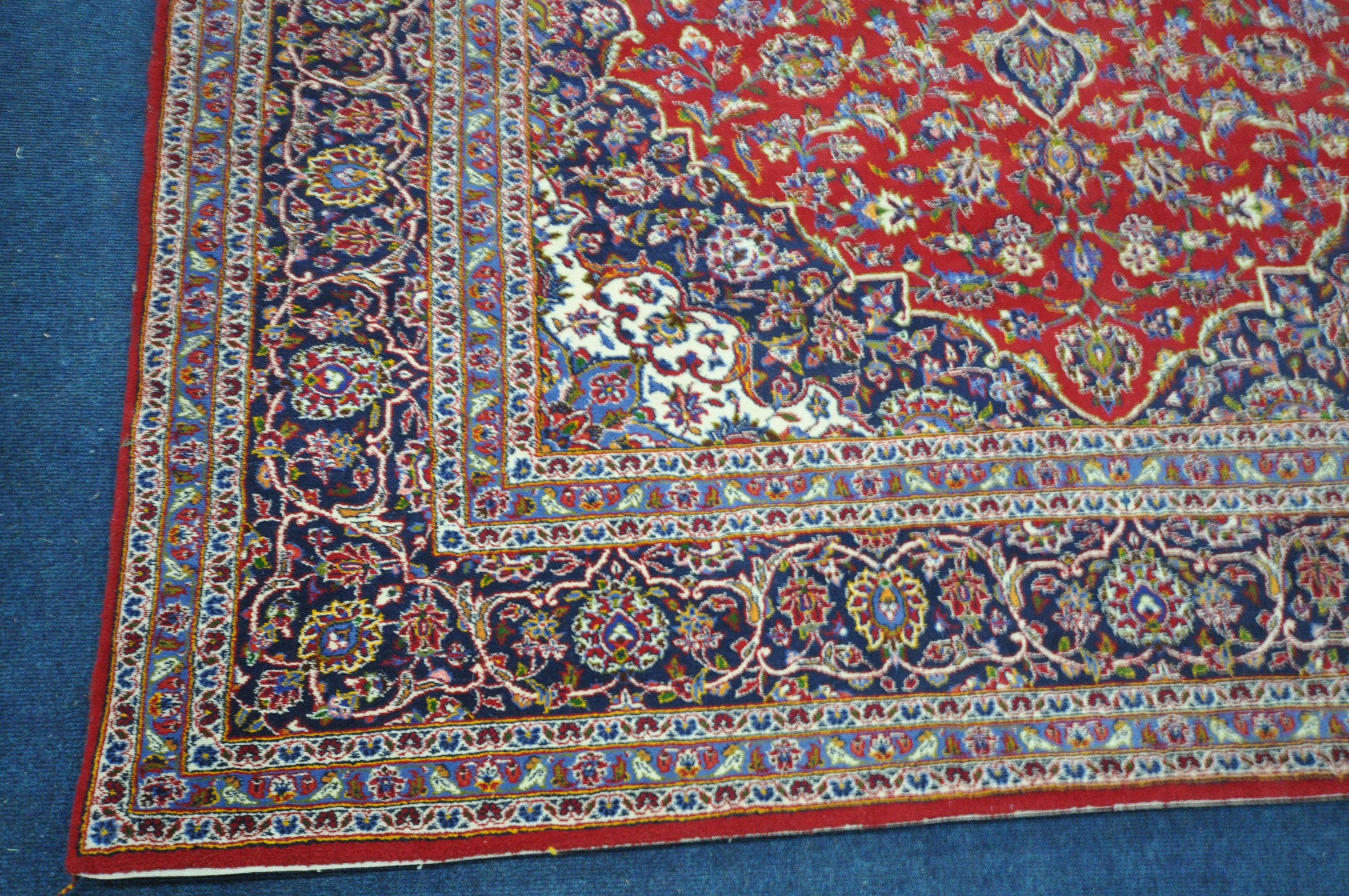 A 20TH CENTURY KASHAN RUG, with a central medallion, within a blue and red field, and a multi - Image 2 of 5