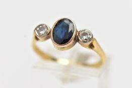 A 18CT GOLD SAPPHIRE AND DIAMOND RING, an oval cut deep blue sapphire bezel set, flanked with two