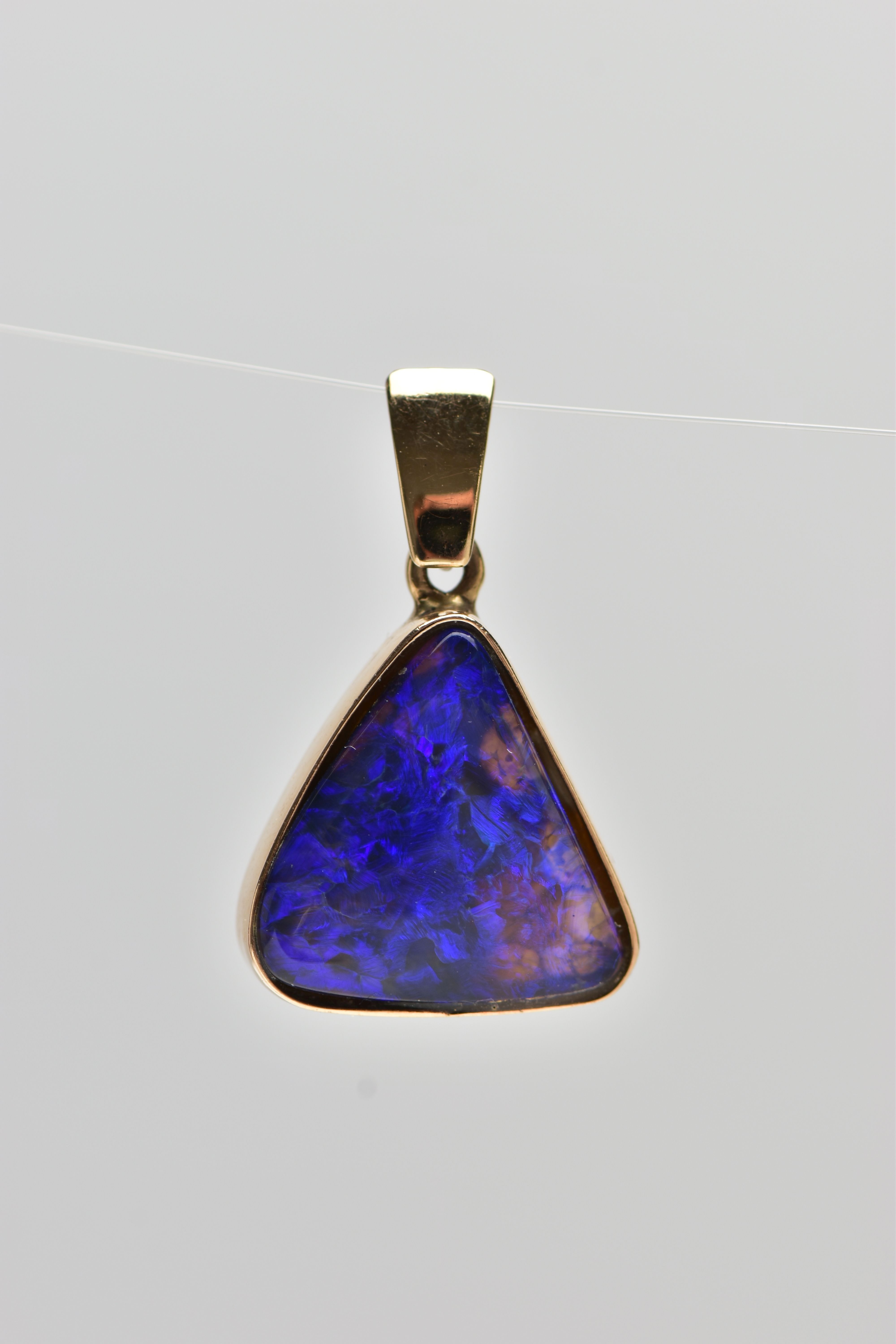 A YELLOW METAL OPAL PENDANT, of a triangular form, set with an opal cabochon displaying blues and