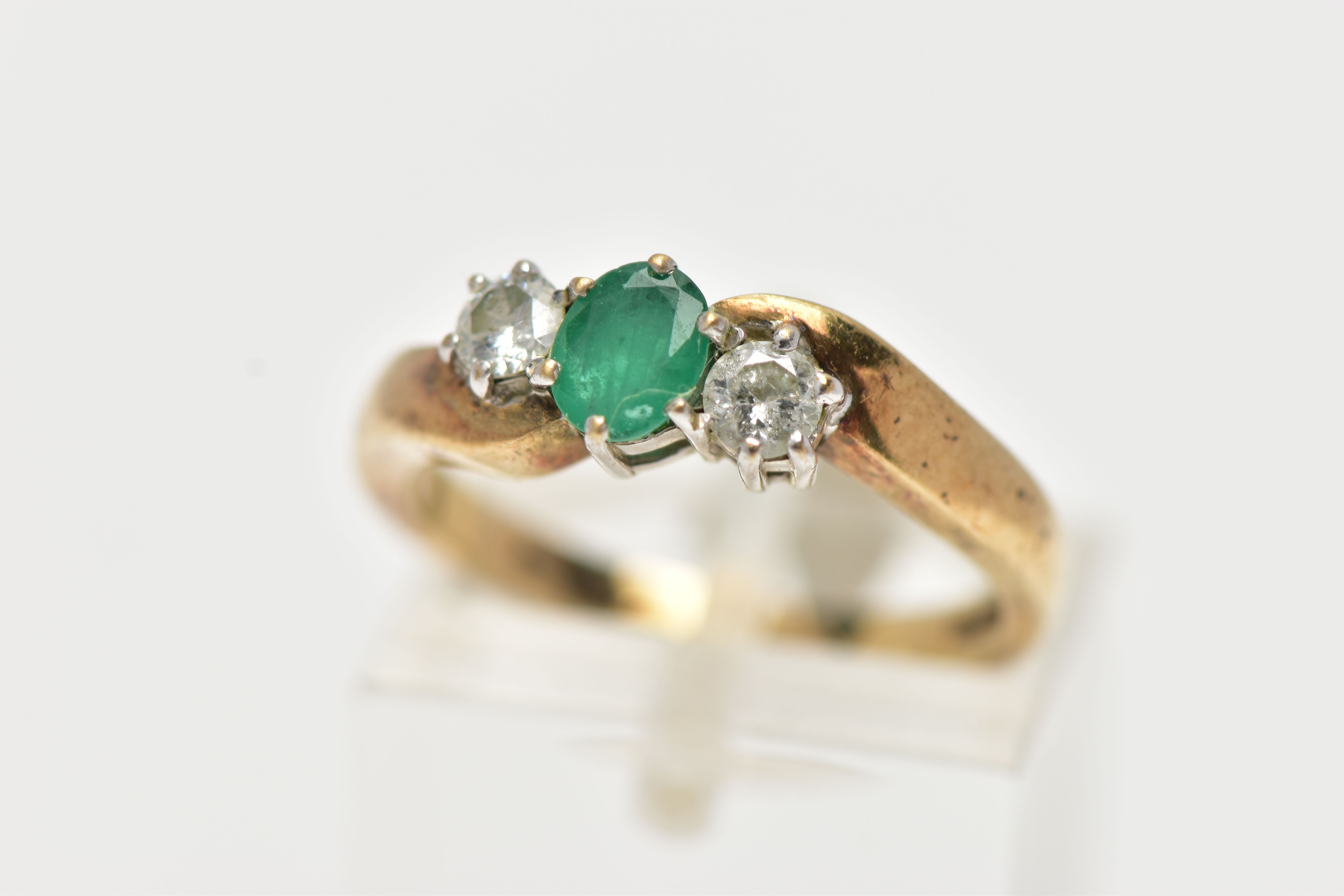 A 9CT GOLD EMERALD AND DIAMOND RING, centrally set with an oval cut emerald in a six claw setting,