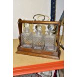 AN OAK TANTULUS WITH THREE MATCHING SQUARE DECANTERS, brass fittings and key (1) (Condition