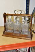 AN OAK TANTULUS WITH THREE MATCHING SQUARE DECANTERS, brass fittings and key (1) (Condition