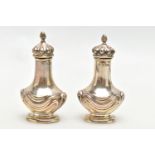 A PAIR OF EARLY 20TH CENTURY SILVER PEPPERETTES, bell shaped pots, each detailed with an embossed