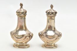 A PAIR OF EARLY 20TH CENTURY SILVER PEPPERETTES, bell shaped pots, each detailed with an embossed