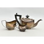 A GEORGE V SILVER THREE PIECE BACHELOR'S TEA SET OF OVAL FORM, the tea pot with ebonised fitments,