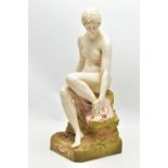 AN EARLY 20TH CENTURY ROYAL DUX FIGURE OF A SEATED NUDE FEMALE BATHER, modelled on a rocky outcrop