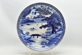 A 19TH CENTURY JAPANESE PORCELAIN CHARGER, primarily painted in underglaze blue with a mountainous