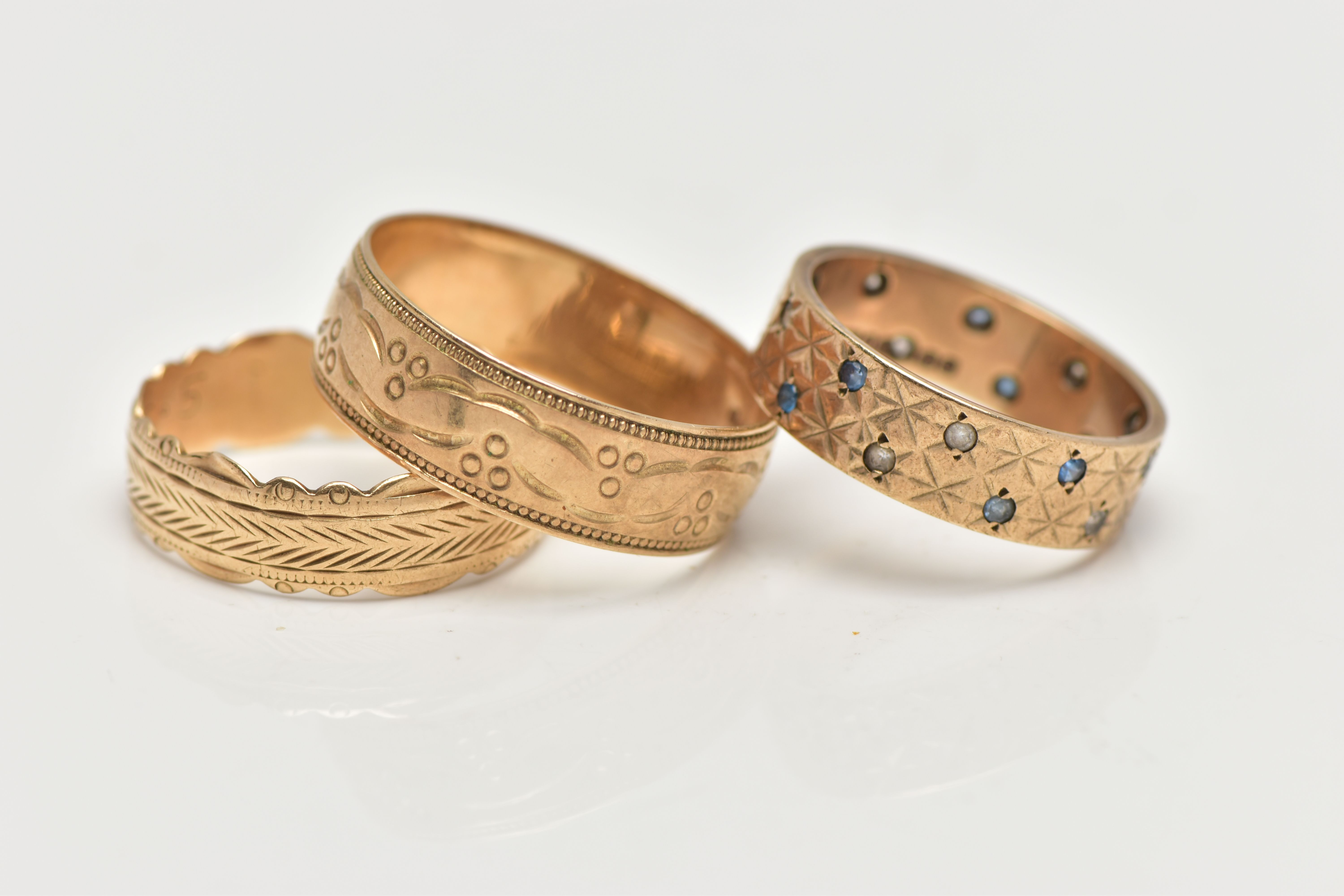 THREE 9CT GOLD BAND RINGS, the first a wide band set with small blue sapphires and spinels, with a