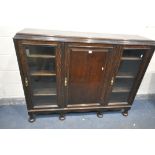 A 20TH CENTURY OAK BOOKCASE, with two glazed doors, flanking a single panelled door, enclosing