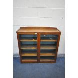 IN THE MANNER OF COTSWOLD SCHOOL, AN OAK GLAZED DOUBLE DOOR BOOKCASE, with a raised back,