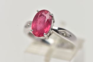 AN 18CT WHITE GOLD RING, centrally set with an oval cut orange/red colour corundum, flanked with two