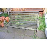 A WOODEN SLATTED GARDEN BENCH with lion mask cast iron ends 131cm wide (Condition very weathered and