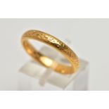 A YELLOW METAL BAND RING, with scroll engraved detail, width of band approximately 4mm, stamped