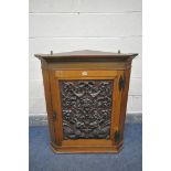 A 20TH CENTURY OAK HANDING CORNER CUPBOARD, with a heavily carved foliate panel, a depicting a