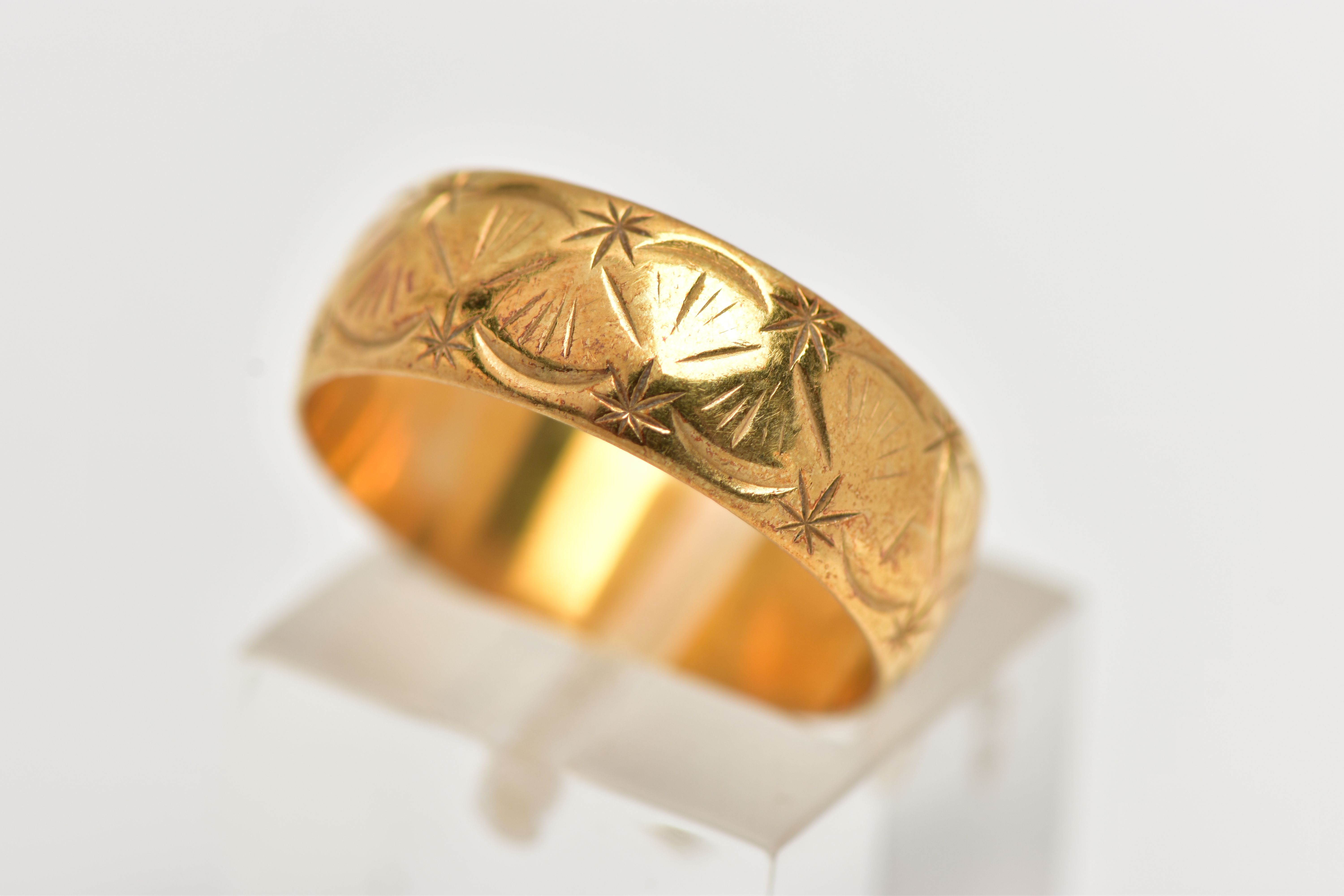 AN 18CT GOLD WIDE BAND RING, decorated with a diamond cut shell pattern, approximate band width 6.