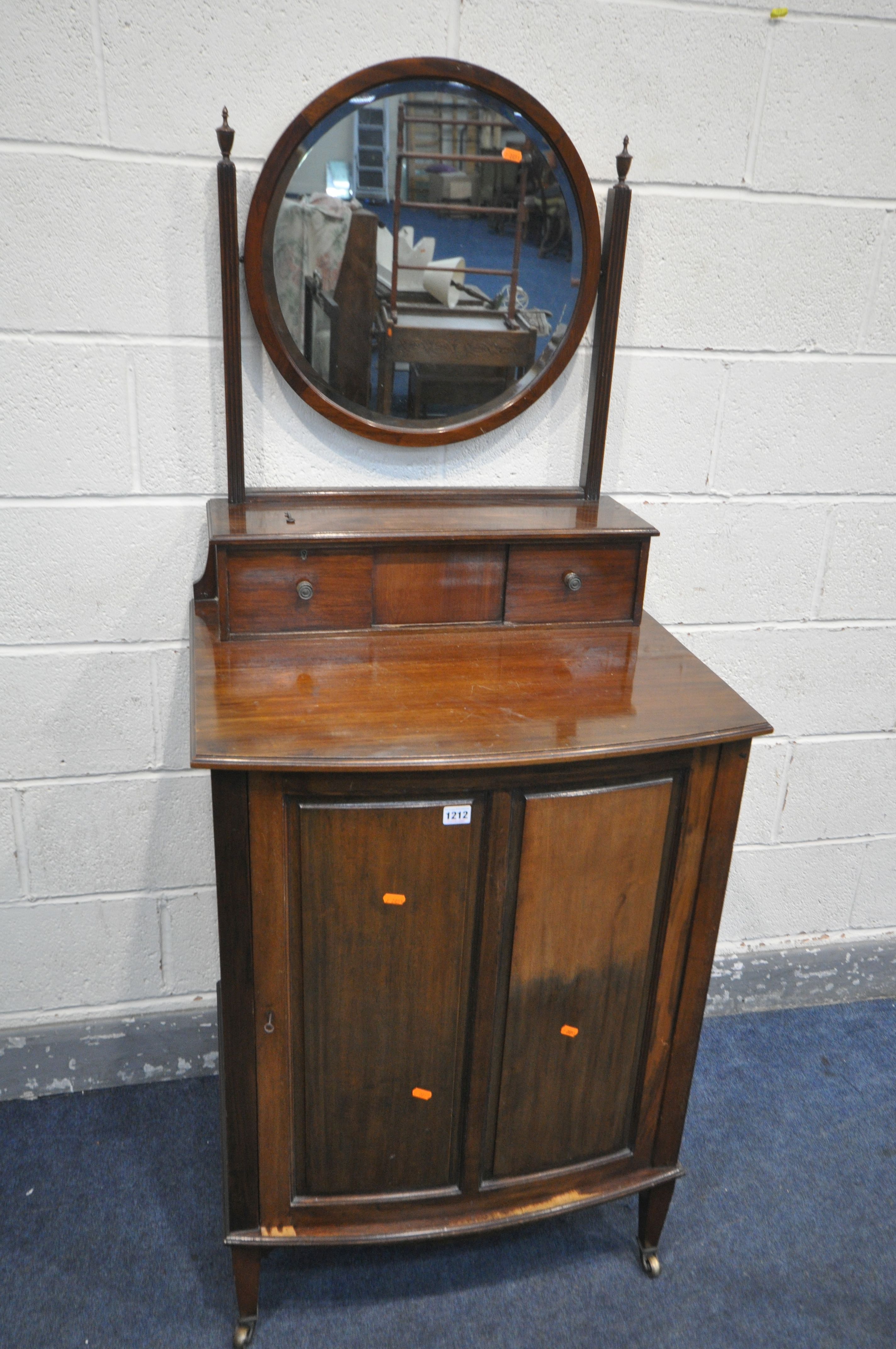 AN EDWARDIAN MAHOGANY BOW FRONT DRESSING CABINET, with a single circular bevelled mirror, two