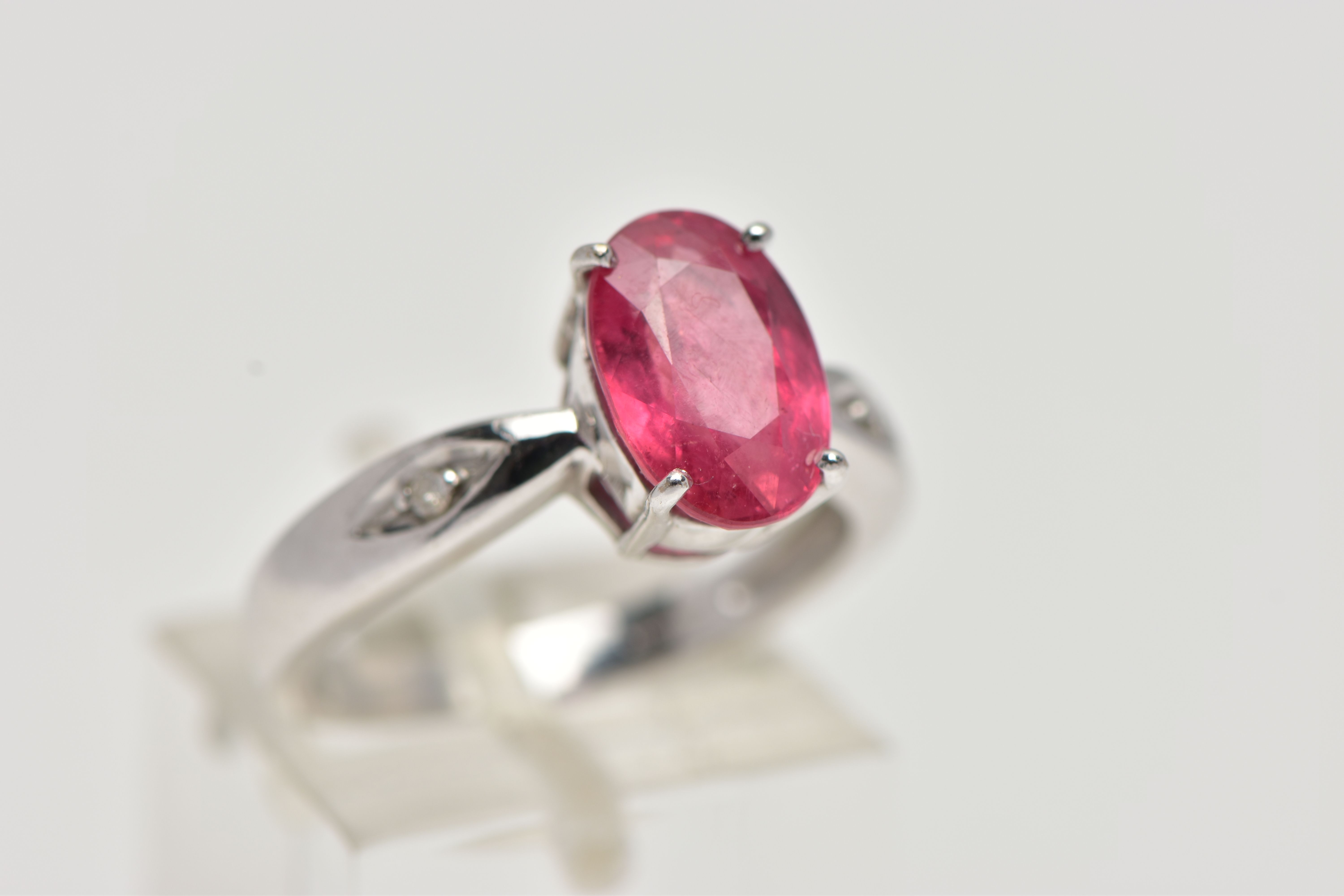 AN 18CT WHITE GOLD RING, centrally set with an oval cut orange/red colour corundum, flanked with two - Image 4 of 4