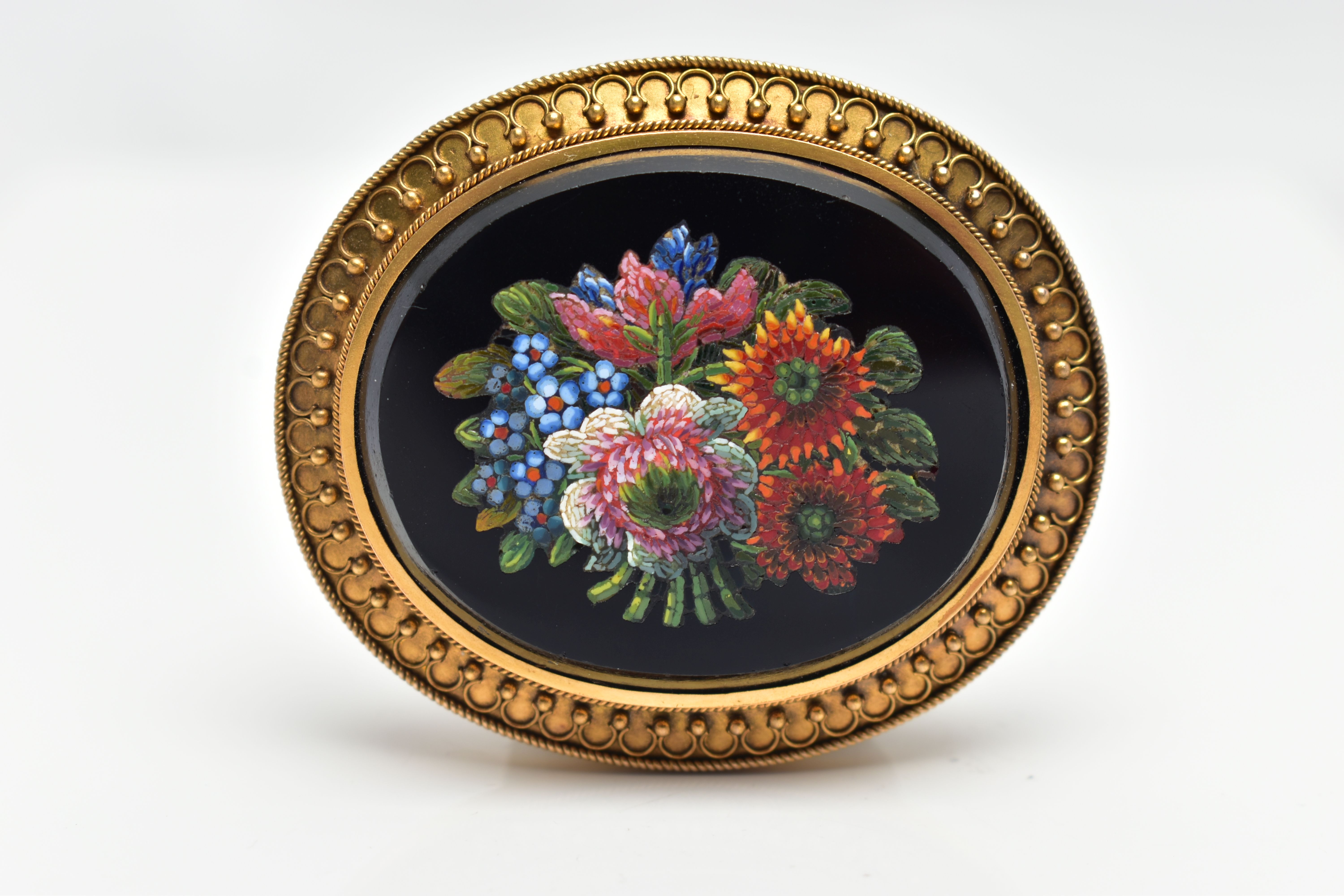 A VICTORIAN MICRO MOSAIC BROOCH, of an oval form, centering on an onyx oval inlay decorated with a