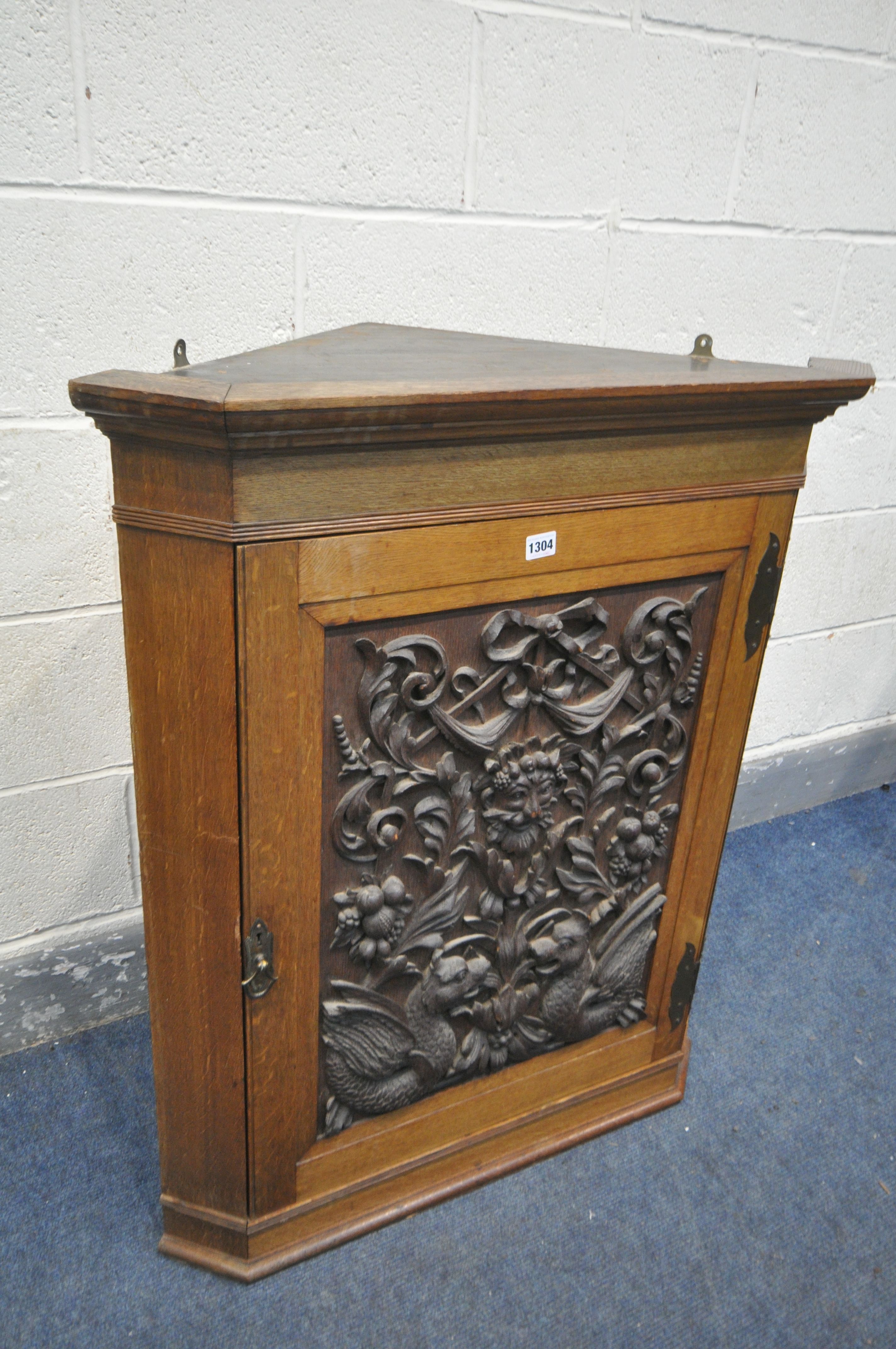 A 20TH CENTURY OAK HANDING CORNER CUPBOARD, with a heavily carved foliate panel, a depicting a - Image 2 of 4
