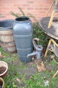 A VINTAGE CAST IRON WATER PUMP mounted on a distressed plywood plinth 57cm high along with a plastic