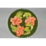 A MOORCROFT POTTERY CHARGER, in Coral Hibiscus pattern on a green ground, printed, painted and