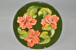 A MOORCROFT POTTERY CHARGER, in Coral Hibiscus pattern on a green ground, printed, painted and