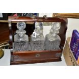 A TWENTIETH CENTURY TANTALUS, with metal mounts, holding three Stuart Crystal square decanters,