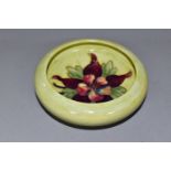 A MOORCOFT POTTERY COLUMBINE INVERTED RIM DISH, Columbine pattern on a pale green ground,