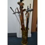 A STICK STAND CONTAINING FENCING FOILS, VINTAGE GOLF CLUBS AND ICE PICKS, the brass stick stand