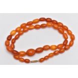 A GRADUATED AMBER BEAD NECKLACE, largest oval bead measuring approximately 14.5mm, smallest