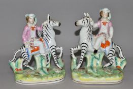 A PAIR OF STAFFORDSHIRE ZEBRAS, each being ridden in a naturalistic landscape, height