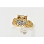 A YELLOW METAL GEM SET RING, in the form of an owl with spread wings, the body is set with single