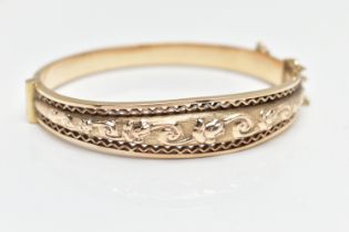 A MID 20TH CENTURY SMITH AND PEPPER 9CT YELLOW GOLD HINGED BANGLE, the front designed as an embossed