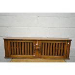 AN ERCOL TWO DOOR HANGING WALL SHELF, with two small internal shelves, length 130cm x depth 24cm x