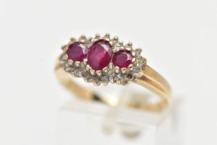 A 9CT YELLOW GOLD RUBY AND DIAMOND CLUSTER RING, designed with three graduated oval cut rubies to