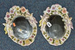 TWO OVAL WALL HANGING PORCELAIN FRAMED MIRRORS, the white porcelain frame is flower encrusted, two