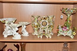 SEVEN CERAMIC PIECES WITH MOULDED CHERUB DECORATION, comprising a centrepiece encrusted with flowers