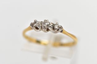 A YELLOW METAL THREE STONE DIAMOND RING, centering on a claw set, round brilliant cut diamond,
