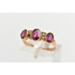 AN EARLY 20TH CENTURY 9CT GOLD GEM SET RING, designed with three oval cut graduated garnets,