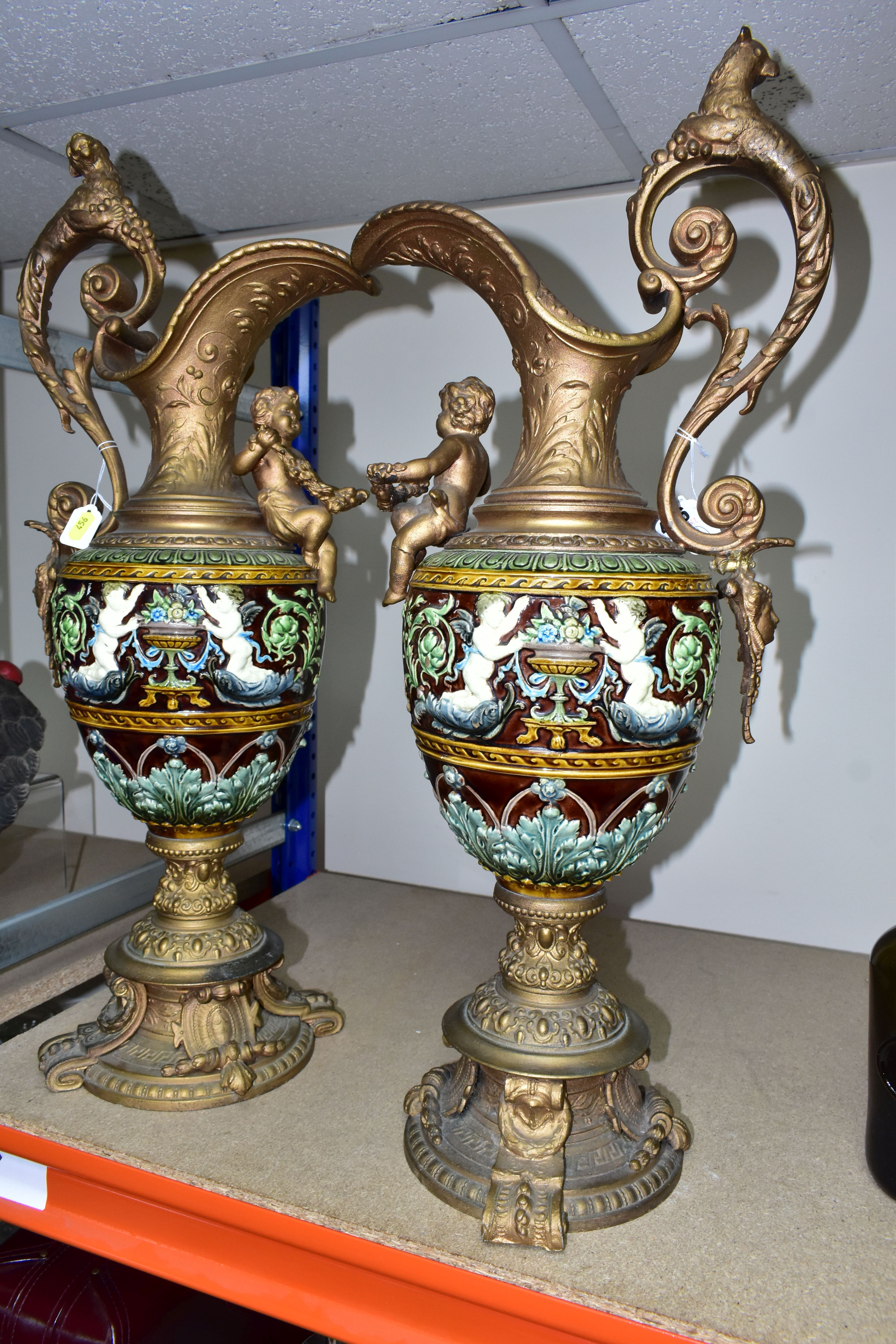 A PAIR OF LATE VICTORIAN GILT SPELTER AND MAJOLICA EWERS, the scrolling handle cast with a beast and